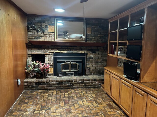 living room with ceiling fan, a fireplace, and wood walls