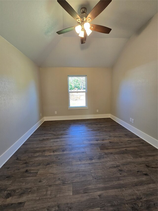 empty room with dark hardwood / wood-style flooring, vaulted ceiling, and ceiling fan