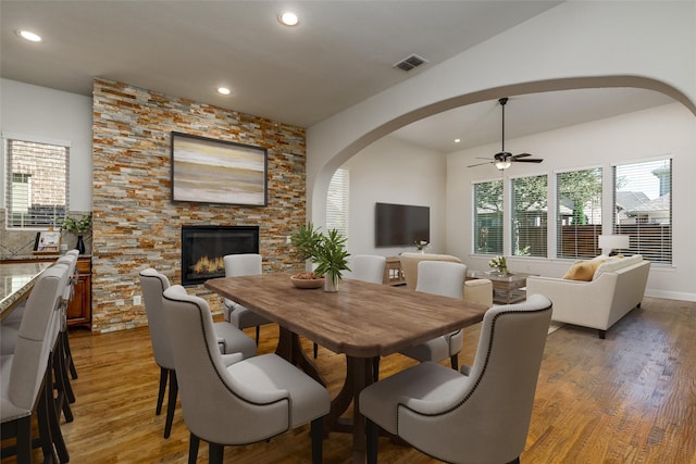 dining space with hardwood / wood-style floors, ceiling fan, and a fireplace