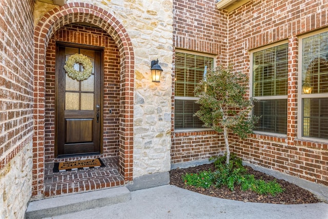 entrance to property featuring stone siding and brick siding