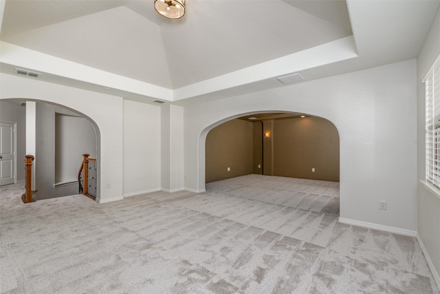 carpeted empty room featuring high vaulted ceiling, arched walkways, and visible vents