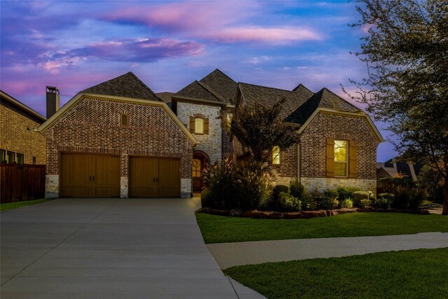 view of front of property featuring a garage and a lawn