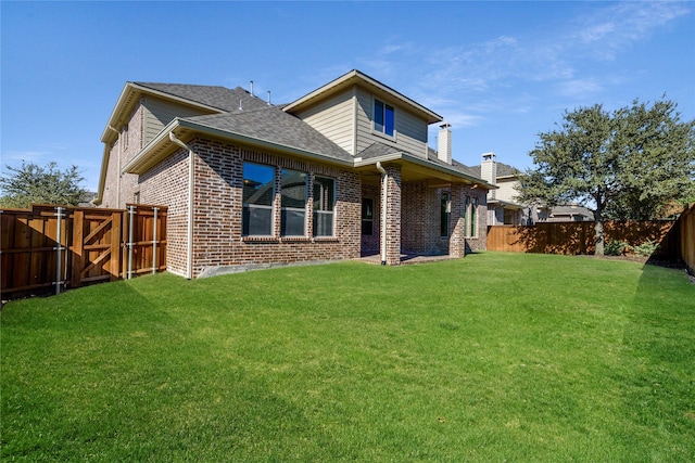 rear view of house with a fenced backyard, brick siding, roof with shingles, a lawn, and a gate