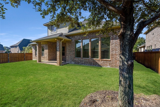 back of property featuring brick siding, a lawn, and a fenced backyard