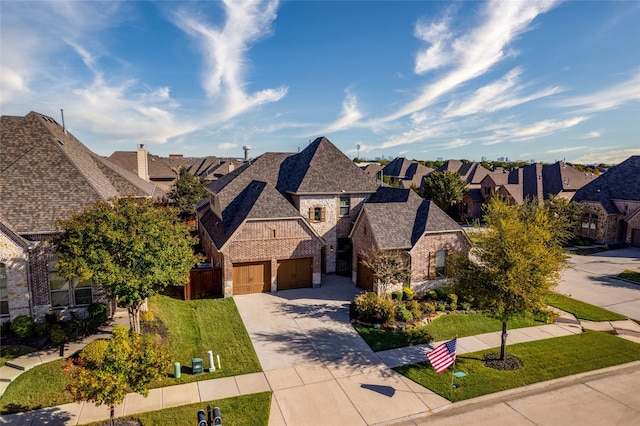 french country style house featuring concrete driveway, stone siding, a residential view, an attached garage, and a front yard