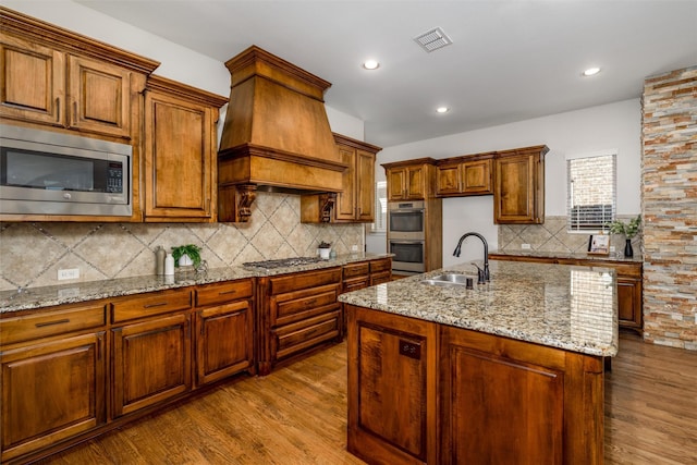 kitchen with stainless steel appliances, a sink, visible vents, dark wood-style floors, and custom range hood