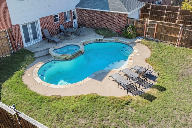 view of swimming pool with fence, a yard, a pool with connected hot tub, french doors, and a patio area