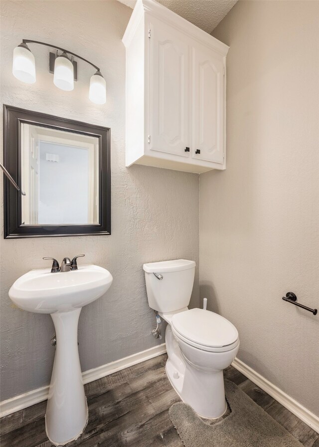 bathroom featuring wood-type flooring, toilet, and sink