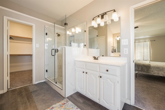 bathroom with vanity, a textured ceiling, hardwood / wood-style flooring, and walk in shower