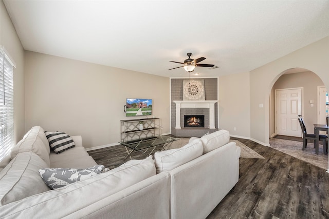 living room with ceiling fan, dark hardwood / wood-style floors, and a brick fireplace