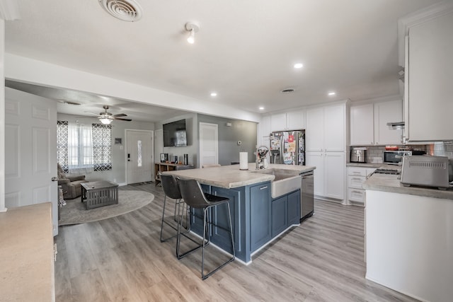 kitchen featuring sink, stainless steel appliances, an island with sink, a breakfast bar area, and white cabinets