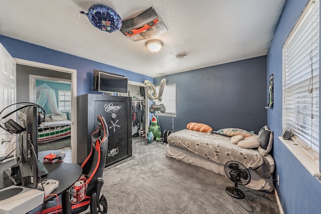 bedroom with carpet floors, a textured ceiling, and multiple windows