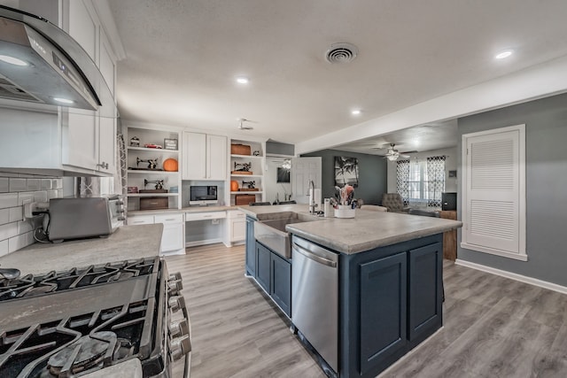 kitchen featuring stainless steel appliances, blue cabinets, ventilation hood, a kitchen island with sink, and white cabinets