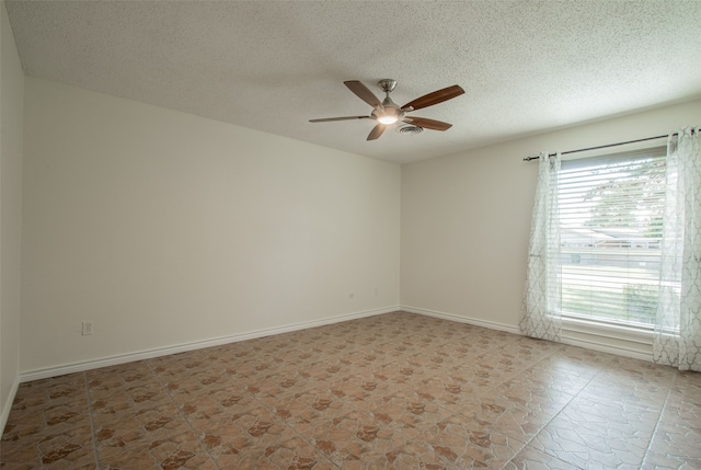 unfurnished room with ceiling fan and a textured ceiling