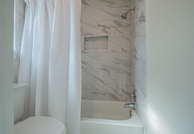 bathroom with tiled shower / bath combo and toilet