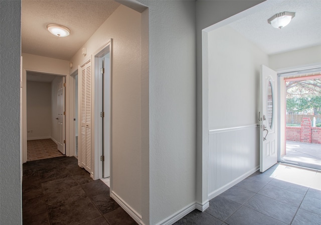 corridor with dark tile patterned floors and a textured ceiling