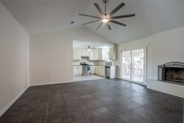 unfurnished living room with ceiling fan, dark tile patterned floors, lofted ceiling, and a brick fireplace