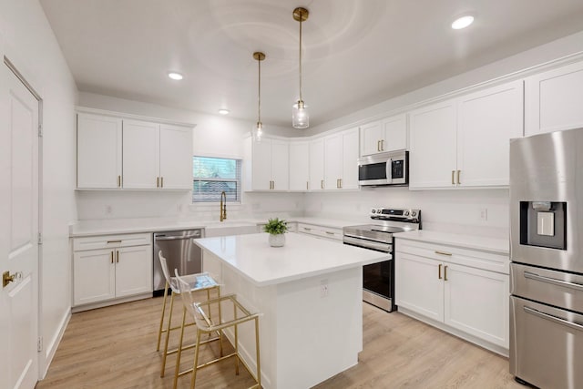 kitchen featuring a center island, stainless steel appliances, white cabinetry, and hanging light fixtures