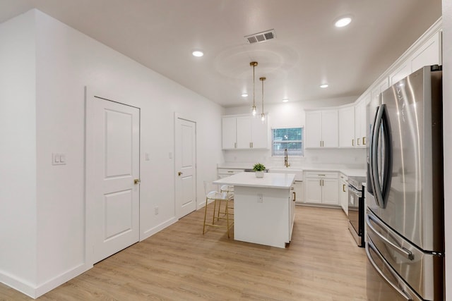 kitchen featuring light wood-type flooring, stainless steel fridge, a center island, and pendant lighting