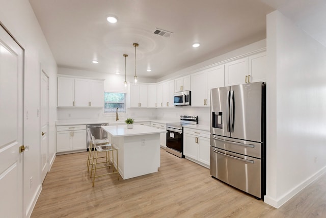 kitchen featuring pendant lighting, a kitchen island, stainless steel appliances, and light hardwood / wood-style flooring