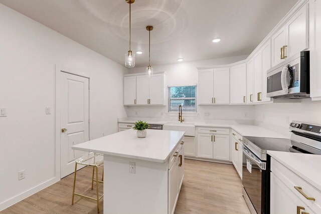 kitchen with a center island, sink, stainless steel appliances, and light hardwood / wood-style flooring