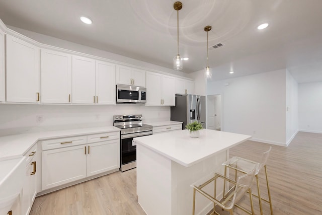 kitchen with a center island, decorative light fixtures, light hardwood / wood-style floors, white cabinetry, and stainless steel appliances