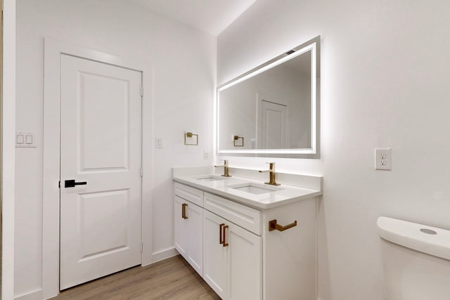 bathroom with hardwood / wood-style floors, vanity, and toilet