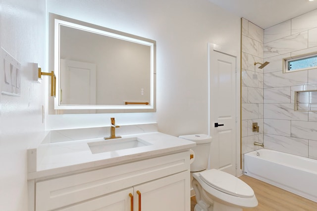 full bathroom featuring hardwood / wood-style floors, tiled shower / bath combo, toilet, and vanity