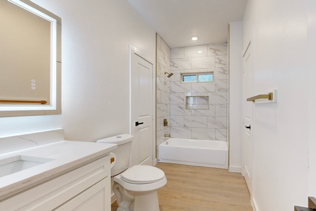 full bathroom featuring vanity, hardwood / wood-style flooring, toilet, and tiled shower / bath combo