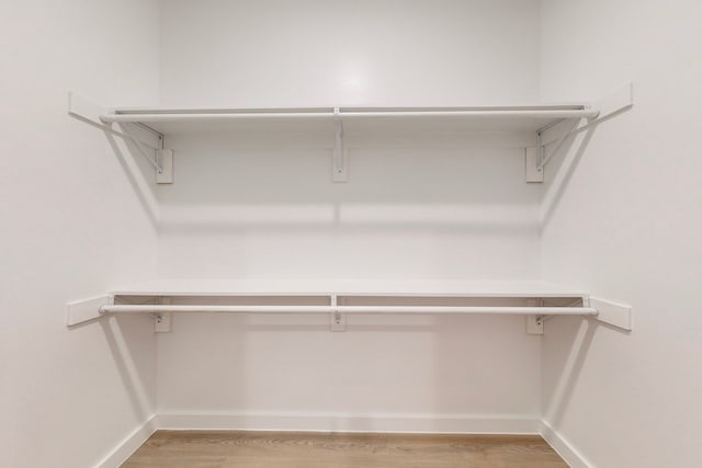 walk in closet with light hardwood / wood-style flooring