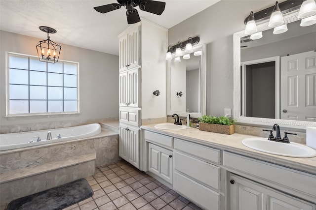 bathroom featuring tile patterned flooring, a relaxing tiled tub, a textured ceiling, vanity, and ceiling fan with notable chandelier