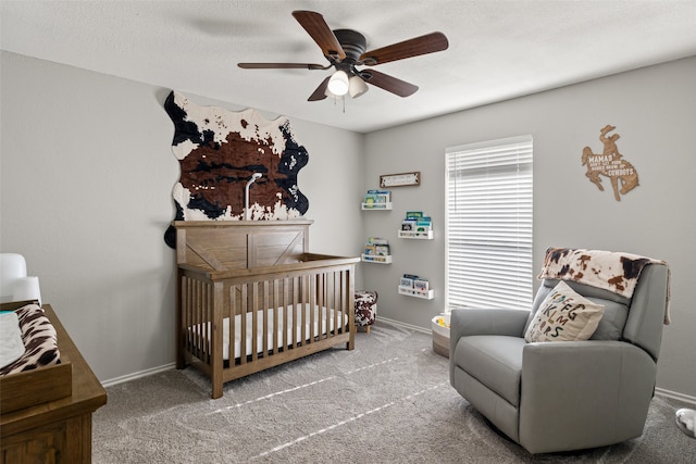 carpeted bedroom with ceiling fan and a crib