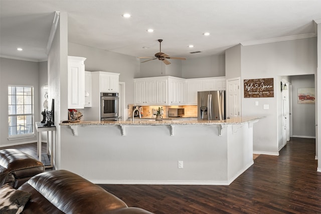 kitchen featuring light stone countertops, dark hardwood / wood-style floors, a breakfast bar area, white cabinets, and appliances with stainless steel finishes