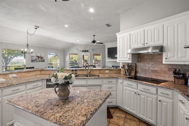 kitchen with kitchen peninsula, tasteful backsplash, sink, white cabinets, and lofted ceiling