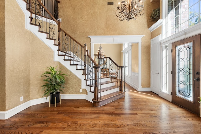 entrance foyer featuring hardwood / wood-style floors, a healthy amount of sunlight, and a high ceiling