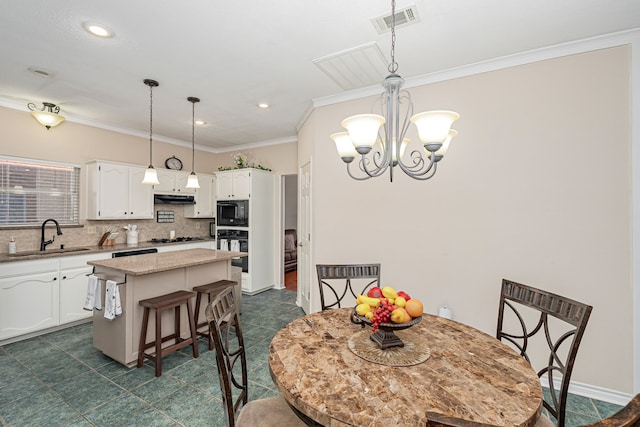 dining area with sink, a chandelier, and ornamental molding