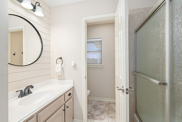 bathroom featuring tile patterned flooring, vanity, toilet, and a shower with shower door