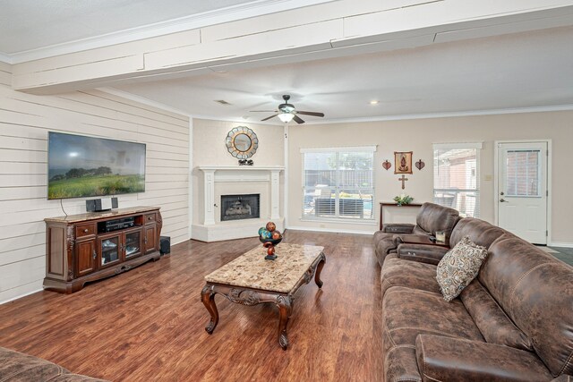 living room featuring ceiling fan, wood walls, dark hardwood / wood-style flooring, and ornamental molding