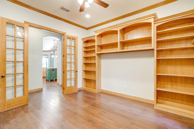 interior space featuring ceiling fan, wood-type flooring, crown molding, and french doors