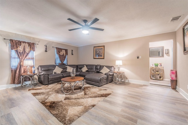 living room featuring ceiling fan, crown molding, a textured ceiling, and light wood-type flooring