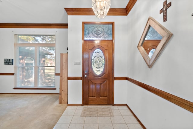 entryway featuring plenty of natural light, light tile patterned floors, a chandelier, and ornamental molding