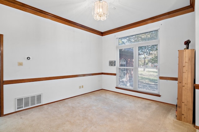 carpeted spare room featuring crown molding and a chandelier