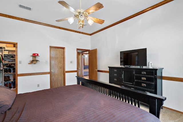 carpeted bedroom with ceiling fan, a walk in closet, crown molding, and a closet