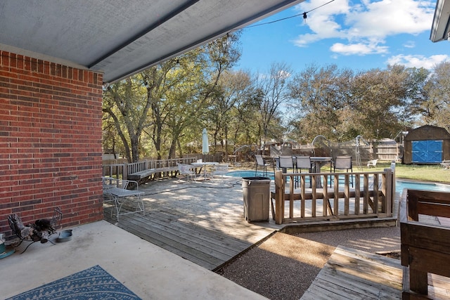 deck featuring a fenced in pool and a storage unit