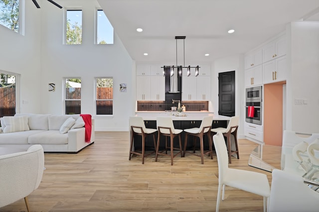 kitchen with a wealth of natural light, a kitchen island with sink, stainless steel appliances, and decorative light fixtures