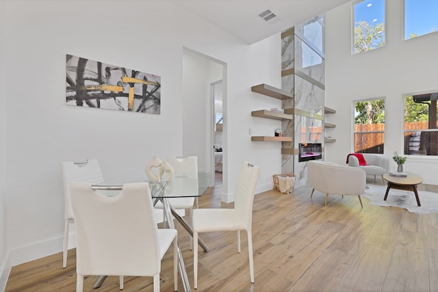 dining room with a healthy amount of sunlight, a high ceiling, and light hardwood / wood-style floors