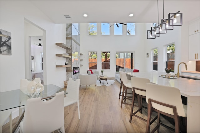 dining room featuring a towering ceiling, light wood-type flooring, and sink