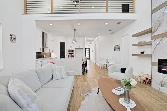 living room with light wood-type flooring, sink, and a high ceiling