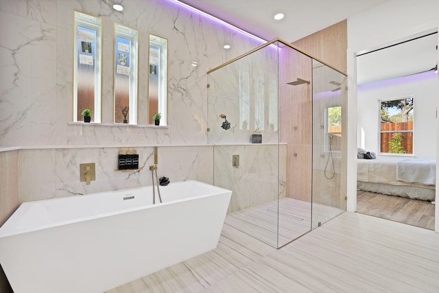 bathroom with hardwood / wood-style flooring, tile walls, and independent shower and bath