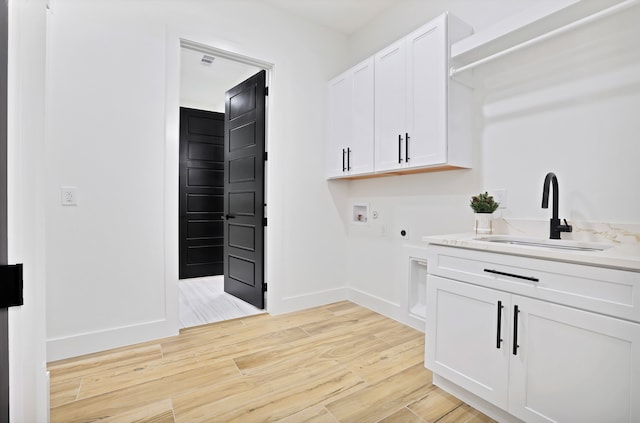 laundry room with electric dryer hookup, cabinets, sink, hookup for a washing machine, and light wood-type flooring